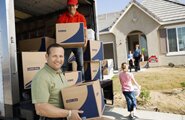 Men moving boxes from a moving truck into a home