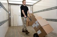 Man in a moving truck pushing boxes on a cart